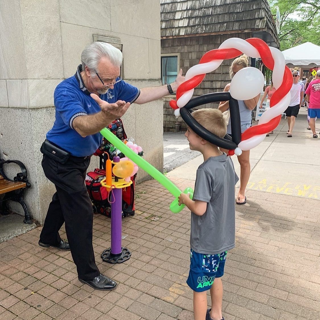 A man puts a balloon hat onto a child's head at the Skaneateles Curbstone Festival